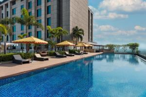 a swimming pool with chairs and umbrellas next to a building at Radisson Blu Hotel New Delhi Paschim Vihar in New Delhi