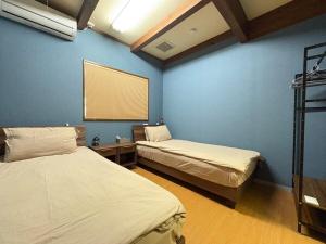 two beds in a room with blue walls at Dons House in Fukuoka