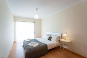 a bedroom with a bed and a table and a window at T2 Arte Xávega in Nazaré