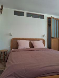 a bedroom with a large bed with purple sheets at l'Annexe, logement confortable avec piscine in Mazan