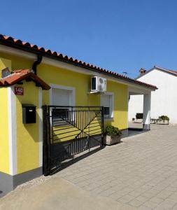 a yellow and white house with a black gate at Apartment Zart 2 in Dekani