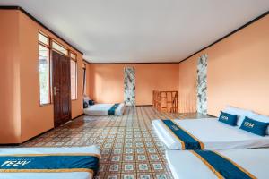 two beds in a room with orange walls at TB Villa Resort By ARBA in Palayangan