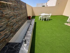 a patio with green grass and a stone wall at فندق حي الربوه Al Rabwah District Hotel in Tabuk