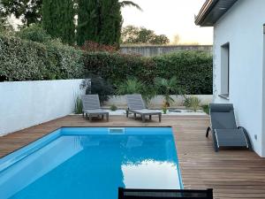 a backyard with a swimming pool and two chairs at STUDIO avec PISCINE in Carmaux