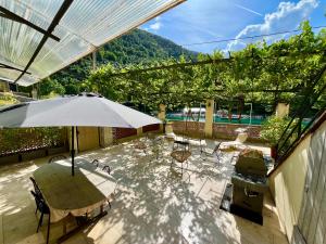 a patio with a table and chairs and an umbrella at Appartement terrasse vue lac in Breil-sur-Roya