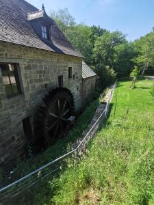 an old stone building with a watermill in a field at Le Moulin in Saint-Nolff
