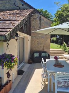 a patio with a table and an umbrella at A La Maison in Les Repôts
