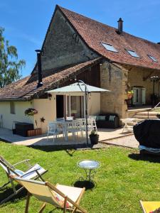 a house with chairs and a table and an umbrella at A La Maison in Les Repôts +12 photos