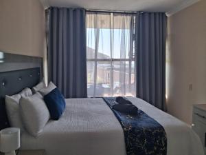 a bedroom with a bed with blue pillows and a window at Ocean Breeze 12 Boulder Bay in Ballito +13 photos
