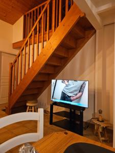 a flat screen tv sitting under a staircase at Maison 3 étoiles à 50m mer plages îles nature piscine chauffée jacuzzi privé WIFI in Le Port-des-Barques