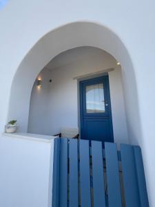 a blue door in a white room with a staircase at Small home Pyrgos in Panormos
