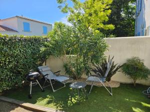 a backyard with two chairs and a grill and two chairs at Maison 3 étoiles à 50m mer plages îles nature piscine chauffée jacuzzi privé WIFI in Le Port-des-Barques