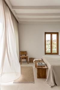 a white bedroom with a bed and a window at ROOTS Nature Living Milos in Adamantas