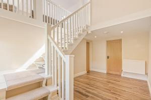 a white staircase in a home with wooden floors at Chestnut Cottage in Bix