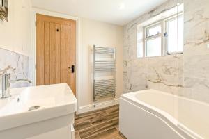 a white bathroom with a tub and a sink at Chestnut Cottage in Bix