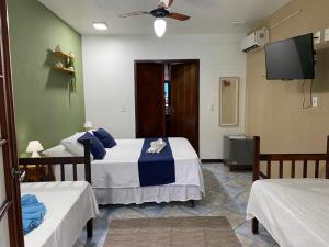 a bedroom with two beds and a flat screen tv at Pousada Aqui é Para-Ti in Paraty