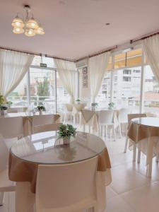a dining room with tables and chairs and windows at Tamanacos Hotel & Spa in Villa Gesell