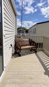 a wooden bench sitting on the side of a building at Seaside Caravan in Leisure Park with WiFi & Parking with decking 2 bedrooms in Rhyl +6 photos