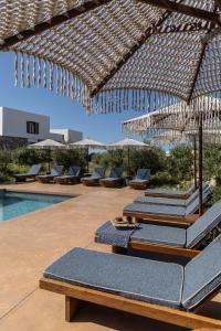 a group of lounge chairs and umbrellas on a patio at ROOTS Nature Living Milos in Adamantas