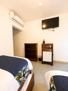 a bedroom with two beds and a flat screen tv at Paradise Jaco Beach Front in Jacó