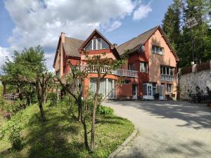 a large red house with trees in front of it at Baroc Boutique Hotel in Topliţa