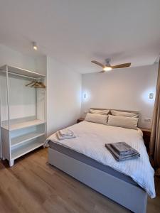 a white bedroom with a bed and a ceiling fan at LEO Apartments in Leonberg