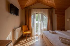a bedroom with a bed and a chair and a window at Hotel Babuda in Mestia in Mestia +25 photos