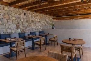 a restaurant with tables and chairs and a stone wall at ROOTS Nature Living Milos in Adamantas