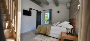 a bedroom with a bed with white sheets and a television at La Cigale dans l'Olivier in Vernègues