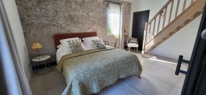 a bedroom with a bed and a brick wall at La Cigale dans l'Olivier in Vernègues +20 photos
