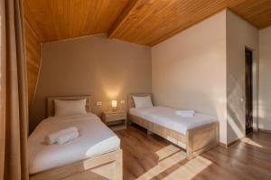 two beds in a room with wooden ceilings at Hotel Babuda in Mestia in Mestia