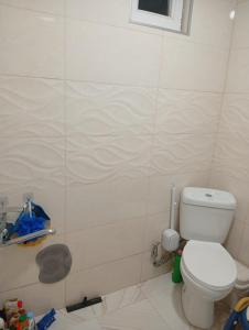 a bathroom with a toilet and a tiled wall at Nika's Home in Ureki +3 photos