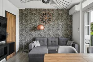a living room with a couch and a clock on a wall at Pop Eurexpo - Parking Privé, Terrasse, Climatisation in Bron