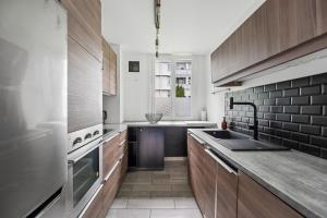 a kitchen with wooden cabinets and a sink at Pop Eurexpo - Parking Privé, Terrasse, Climatisation in Bron
