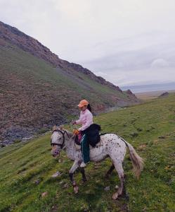 a woman riding a horse in a field at Zalkar Yurt Camp in Song-Kul