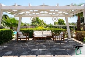a white pergola with chairs and a couch on a patio at Hotiday Gallipoli Sannicola in Gallipoli