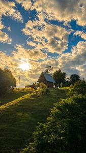 a barn in a field with a cloudy sky at Chalés Recanto da Serra in Bocaina do Sul
