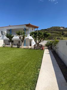 a house with a green lawn and a sidewalk at Waves Of Eros in Paralía