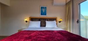 a bedroom with a large bed with a red blanket at Mouria Pension Rooms & Studios in Ancient Epidauros +53 photos