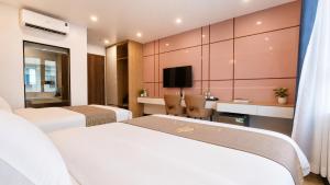 a hotel room with two beds and a tv at Hestia Hotel Móng Cái in Móng Cái +5 photos