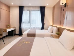 a hotel room with two beds and a window at Hestia Hotel Móng Cái in Móng Cái