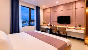 a hotel room with a bed and a desk and a tv at Hestia Hotel Móng Cái in Móng Cái