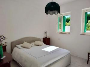 a bedroom with a bed with white sheets and two windows at Bianco e Rosmarino in Selva di Fasano