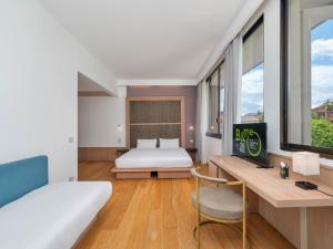 a bedroom with a bed and a desk and a bed and window at B&B HOTEL Padova Methis in Padova +36 photos