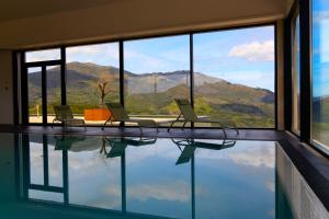 a room with a pool with two chairs and a window at Hotel Mezio National Park in Soajo