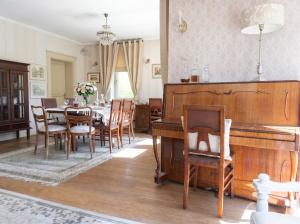 a dining room with a table and a piano at Golden Villa Kraków - Stylowa Willa z Ogrodem i Grillem in Węgrzce