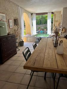 a dining room with a wooden table and a swimming pool at Les 3 contes in Vallabrix