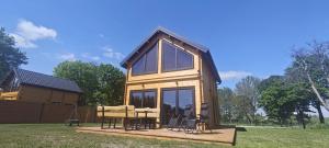 a tiny house on a wooden deck with windows at Mazurska Puszcza domek pod brzozą in Dźwierzuty