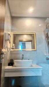 a bathroom with a white sink and a mirror at Hestia Hotel Móng Cái in Móng Cái