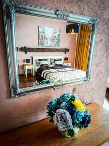 a mirror reflecting a bedroom with a bed and a vase of flowers at Apartments Sofia - Luxury Penthouse in Liptovský Mikuláš +45 photos